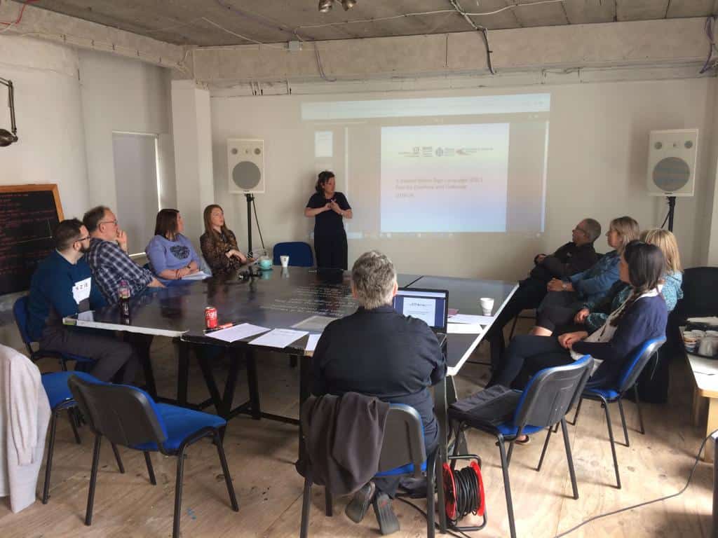 People attending a conference on the BSL (Scotland) Act 2015 in a meeting room.