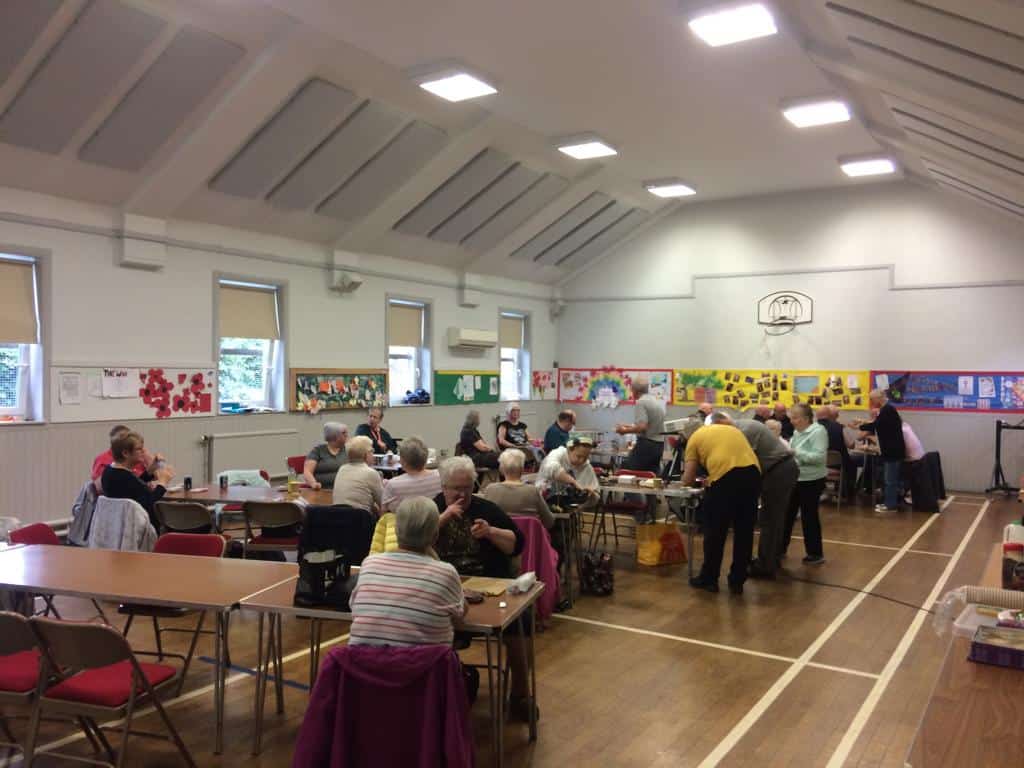 People participating in a community event in a hall, some seated and some standing.