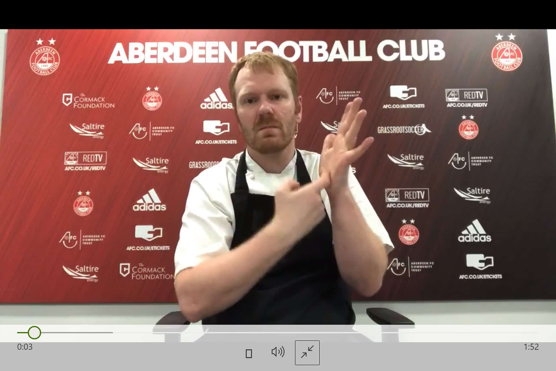 Man demonstrating British Sign Language at Aberdeen Football Club event.