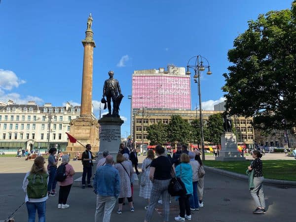 Group of people protesting for Scottish Sign Language rights in a city square.