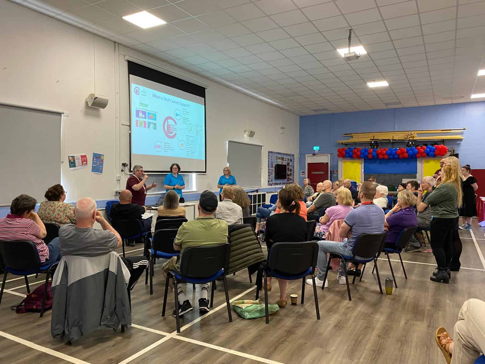 People attending a presentation on the BSL (Scotland) Act 2015 in a community hall.