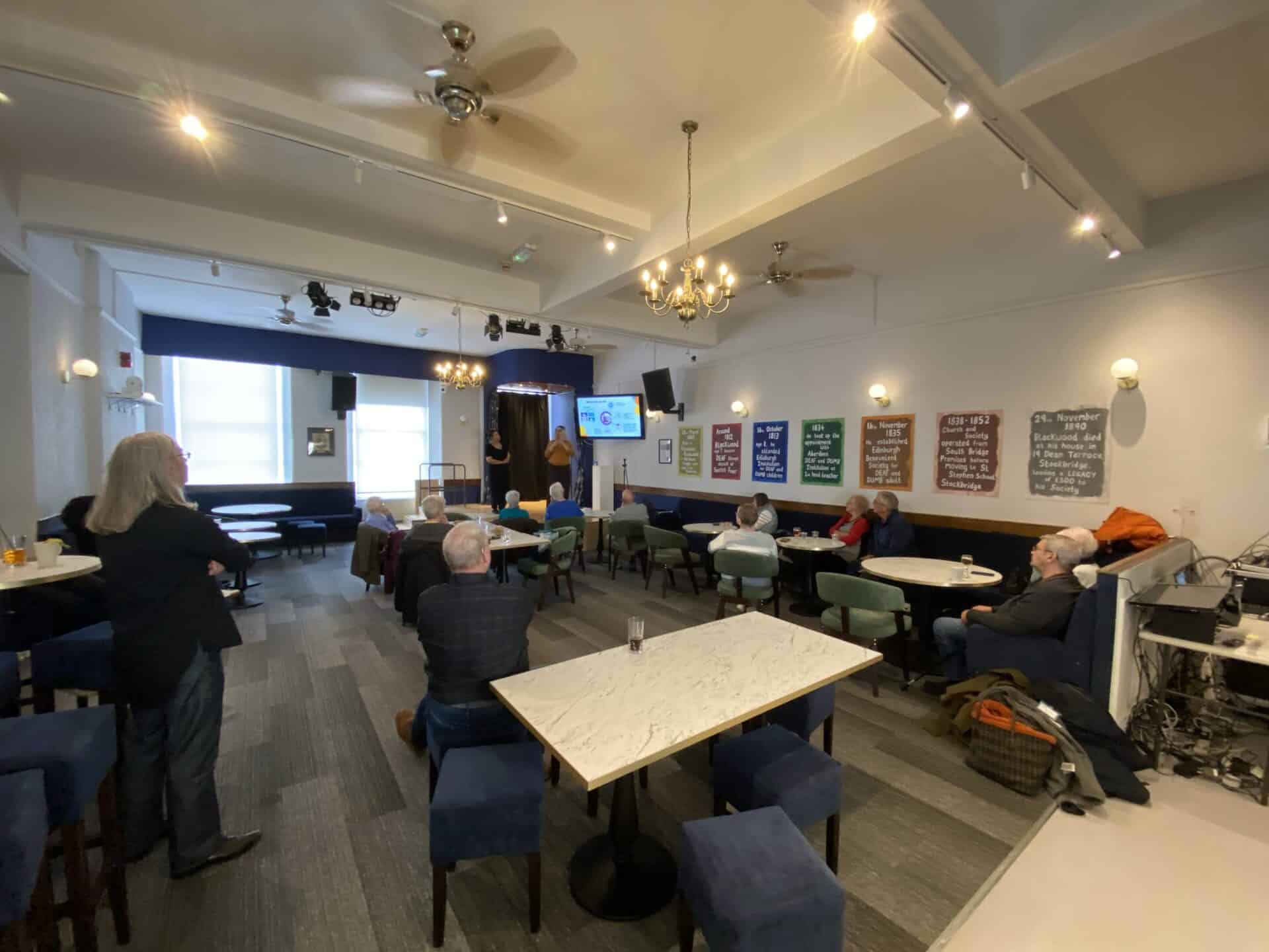Community members attending a meeting about BSL (Scotland) Act 2015 in a modern room.