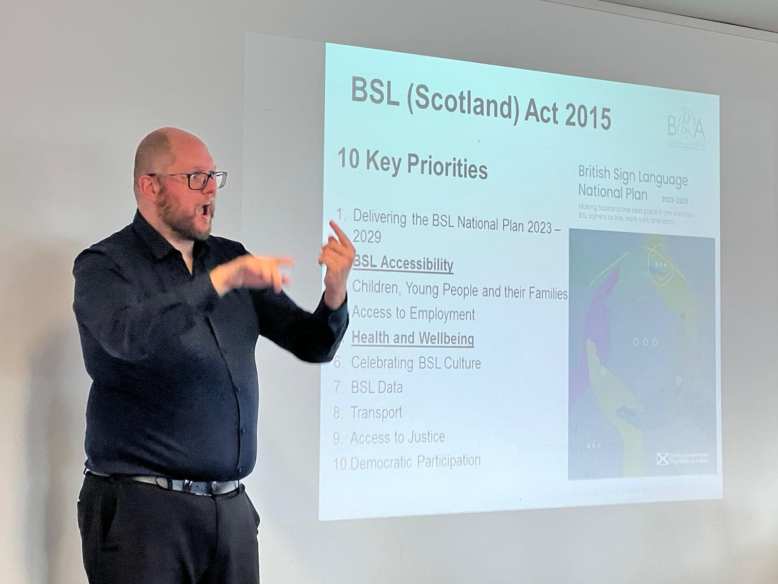 Man presenting BSL Scotland Act 2015 key priorities and accessibility goals.