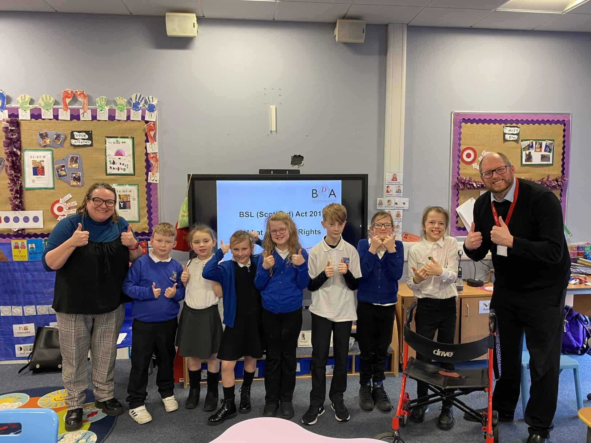 Group of children and adults in classroom promoting BSL Scotland Act 2015.