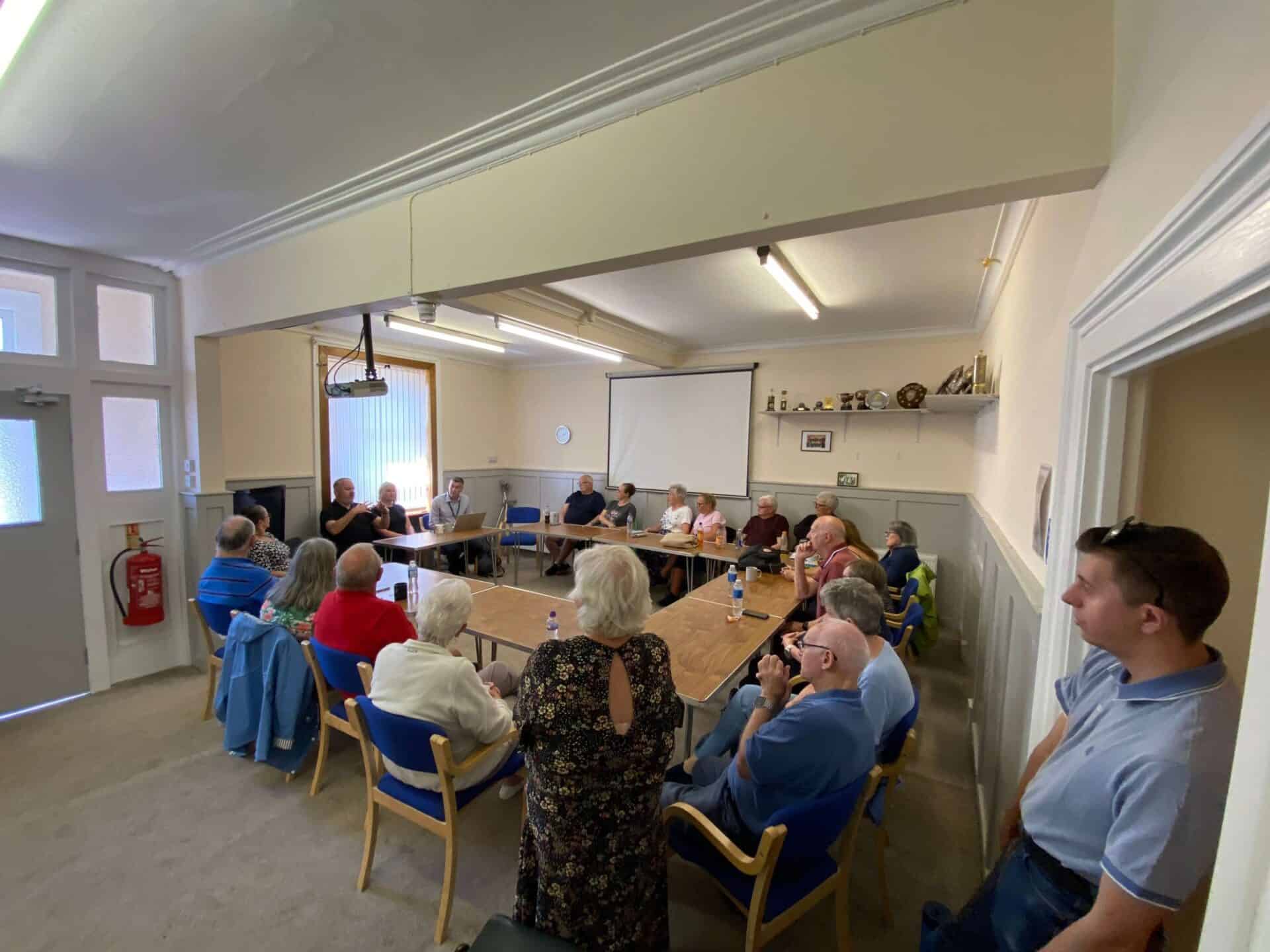 Community meeting discussing the BSL (Scotland) Act 2015 in a classroom setting.