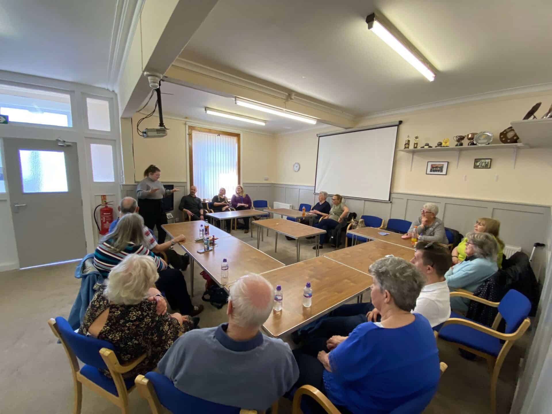 Community meeting discussing the BSL (Scotland) Act 2015 in a classroom setting.