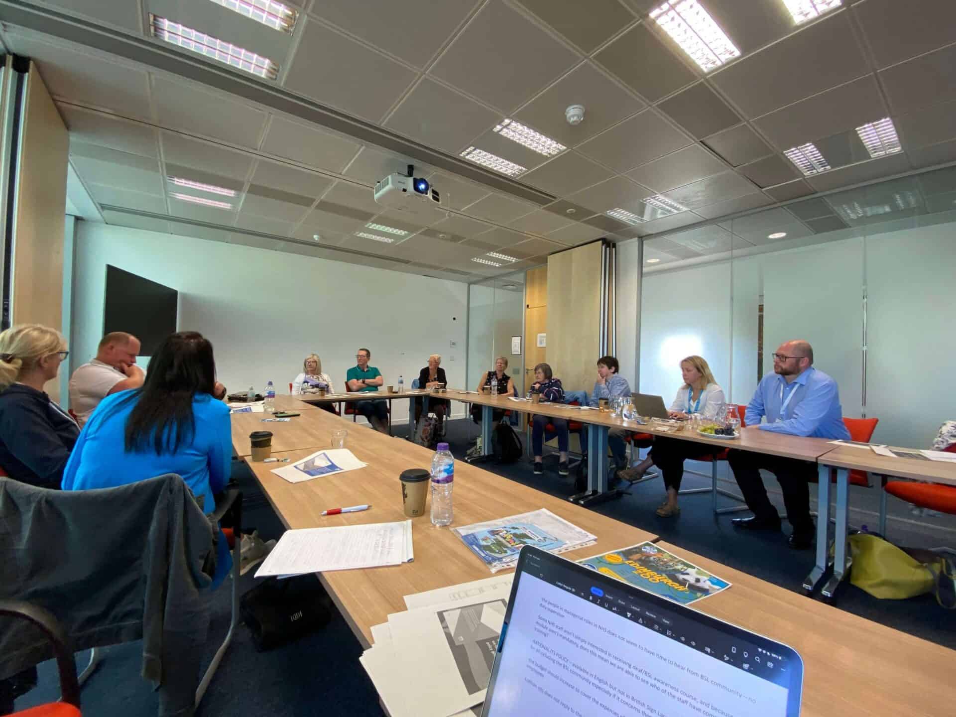 Group of people in a conference room discussing BSL (Scotland) Act 2015.
