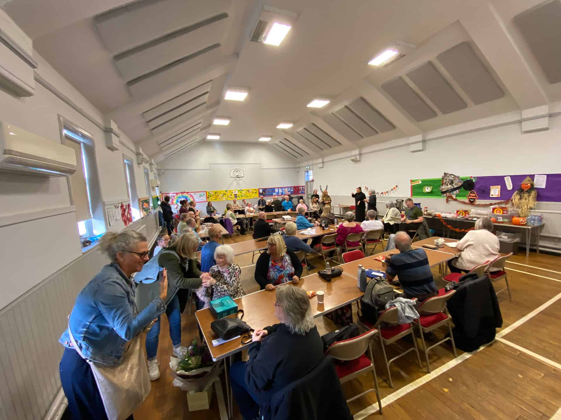 Community gathering discussing BSL (Scotland) Act 2015 in a hall.