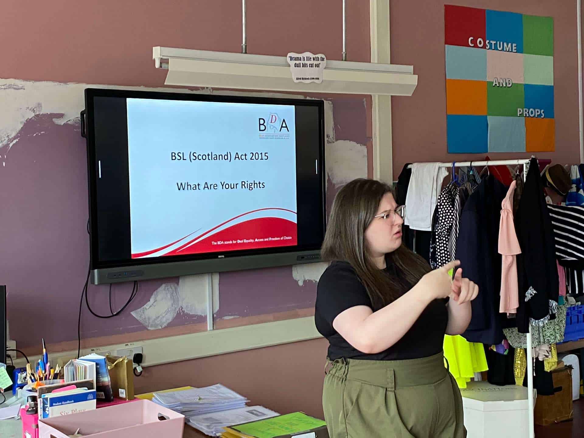 Young woman presenting BSL (Scotland) Act 2015 rights in classroom.